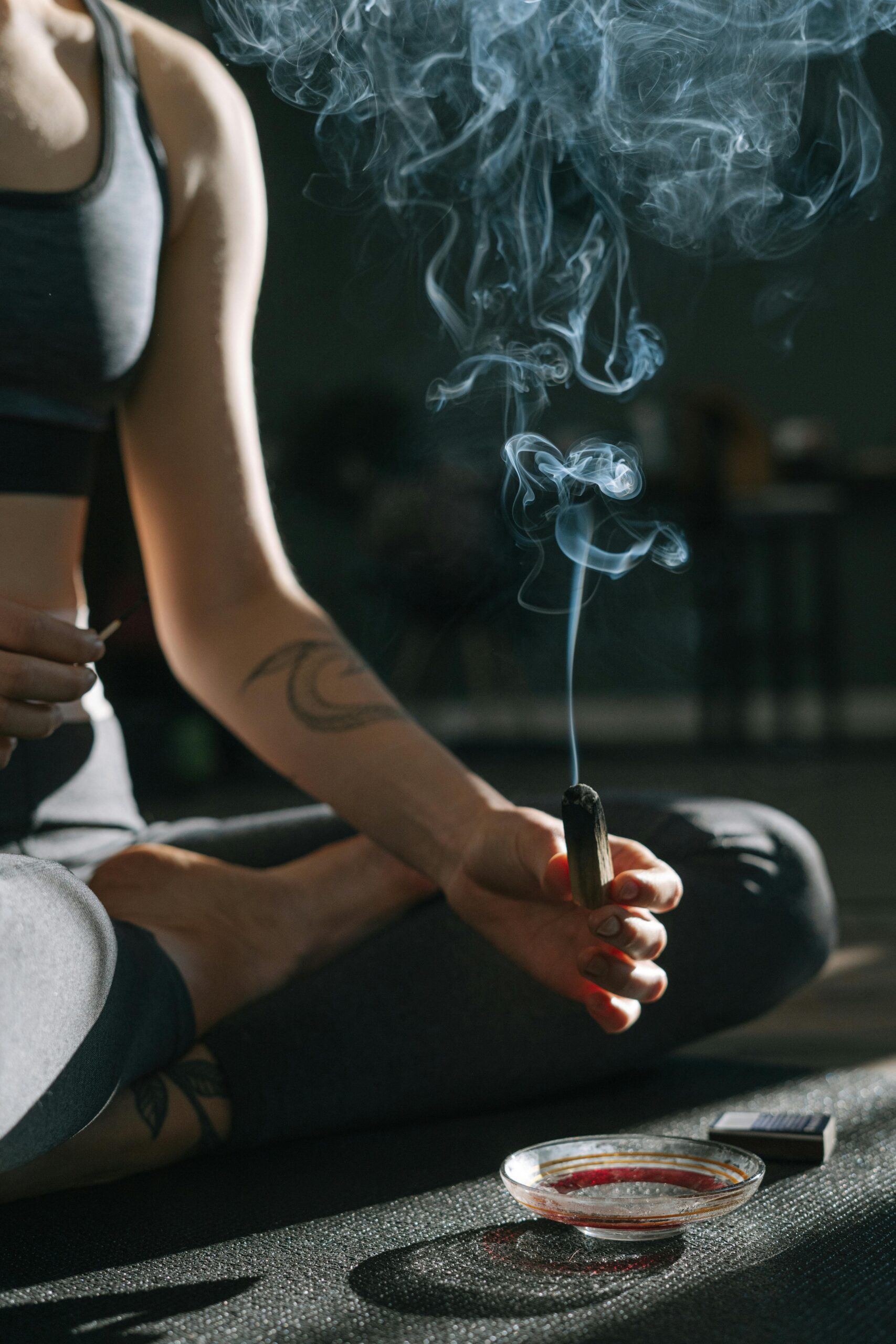 A person practicing meditation holding burning incense with smoke rising gently.
